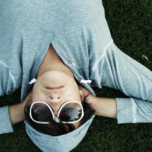 戴墨镜穿卫衣的男孩躺在草地上